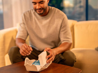 A person holding an unopened IQOS device box.