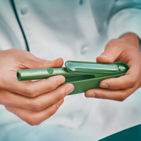 Close up of a chef's hands opening a jade green IQOS ILUMA device.