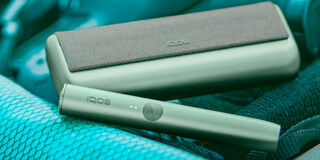 A person holding an unopened IQOS device box.