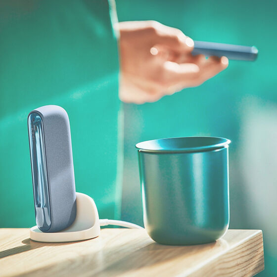 An IQOS device on a desk next to papers.