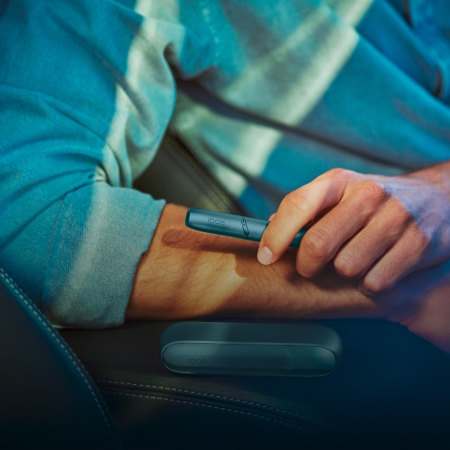 Hands using IQOS Originals Duo holder in turquoise color.