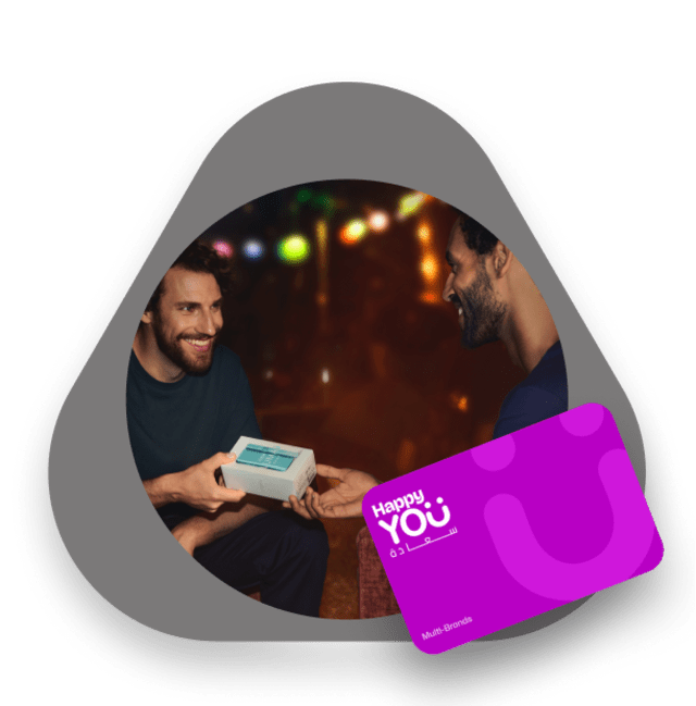 Two smiling men exchanging a turquoise IQOS gift box, with a purple Happy You gift card shown in the foreground.