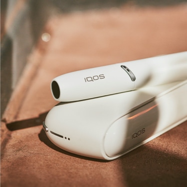 A white IQOS device and holder.
