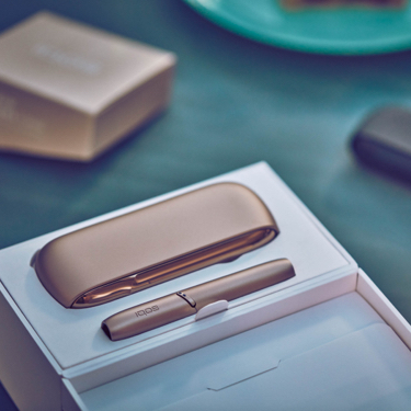 Gold IQOS DUO in its packaging on a blue table