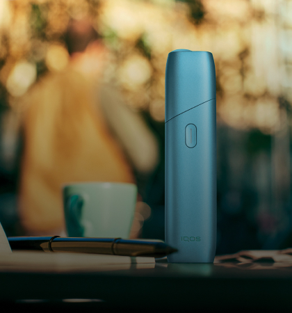 Turquoise IQOS Originals One device on a coffee table.