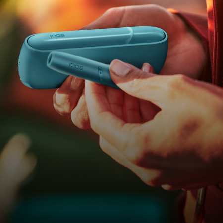 Hand holding IQOS Originals Duo holder and pocket charger in turquoise color.